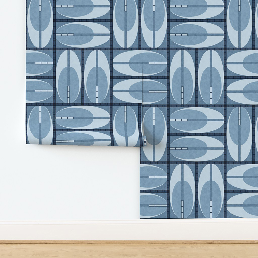 The artwork features a repeating geometric pattern of symmetrical shapes resembling elongated, curved diamonds or petals in various shades of blue and green. Each shape is split vertically with one half filled with a light blue and the other half filled with green or darker blue. The background is a light, almost pastel blue, which provides a soft yet vibrant backdrop. One of the blue shapes near the upper left contains a white starburst element, adding a focal point of brightness to the composition. The overall design conveys a modern, mid-century aesthetic with clean lines and harmonious color contrasts.